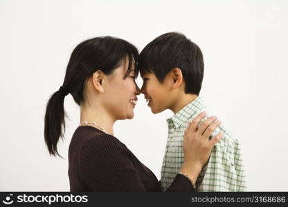 Asian mother and young son touching noses and smiling.