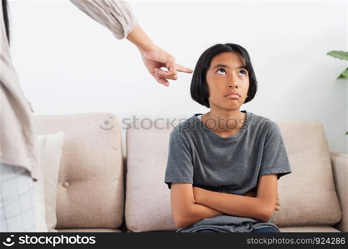 Asian mother is angry and scold her daughter while sitting on the sofa because of bad behavior. The concept of domestic violence.