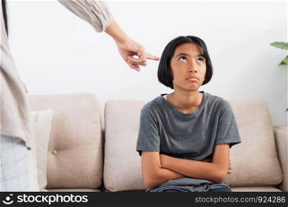 Asian mother is angry and scold her daughter while sitting on the sofa because of bad behavior. The concept of domestic violence.