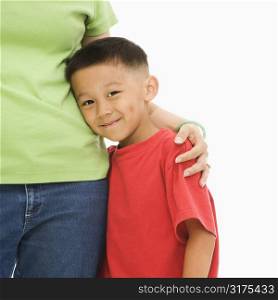 Asian mother standing with arm around son.