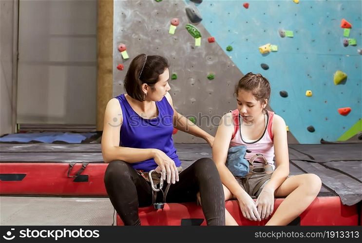 Asian mother teaching her caucasian daughter to climbing rock for indoor sport. Activity, Family and Education Concept.