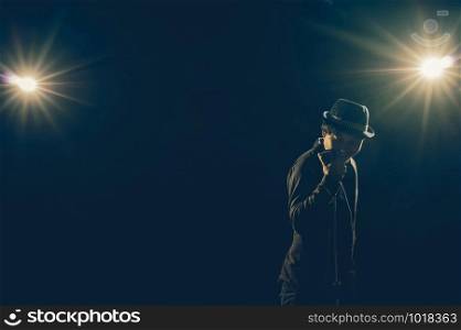 Asian Musician singing a song with microphone on black background with spot light and lens flare, musical concept