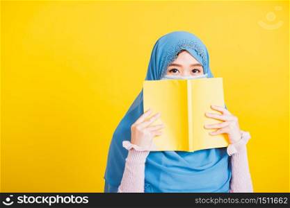 Asian Muslim Arab, Happy beautiful young woman religious wear veil hijab and face mask to prevent coronavirus she student hold books close face, isolated on yellow background, Back to college