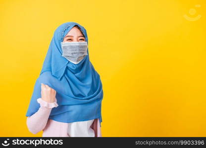 Asian Muslim Arab, Portrait of happy beautiful young woman Islam wear veil hijab and face mask protect raise hands glad excited cheerful after recovering from illness coronavirus isolated yellow
