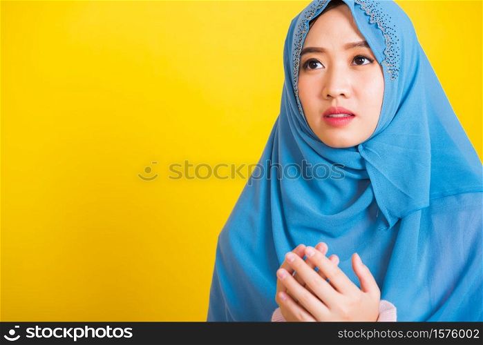 Asian Muslim Arab, Portrait of happy beautiful young woman religious wearing veil hijab she henna decorated hands praying to Allah God, isolated on yellow background, Eid Mubarak and soul fasting
