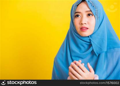 Asian Muslim Arab, Portrait of happy beautiful young woman religious wearing veil hijab she henna decorated hands praying to Allah God, isolated on yellow background, Eid Mubarak and soul fasting