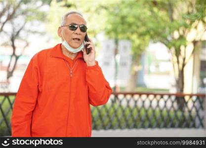 asian old asian elderly senior elder man talking on smart mobile phone outdoor