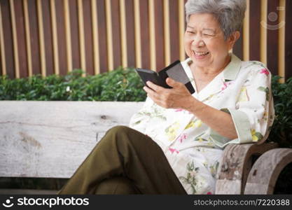 asian old asian elderly senior elder woman talking on smart mobile phone outdoor