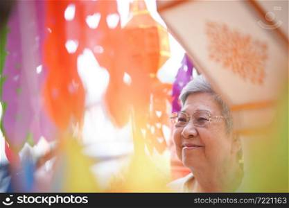 asian old elderly elder woman with hanging decorative festive paper lantern