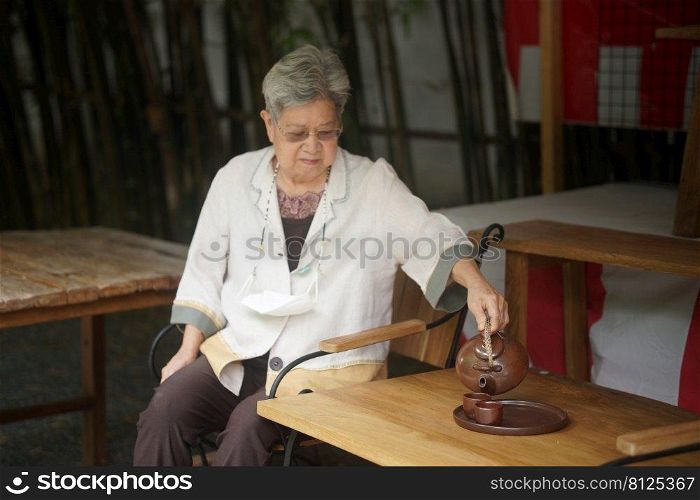 asian old elderly female elder woman drinking hot tea in garden. senior leisure lifestyle
