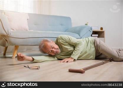 Asian old man lying on floor after falling down with wooden walking stick, Sick senior man beside couch on rug in living room at home, Elderly having an accident after doing physical therapy alone