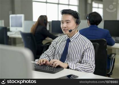 Asian Operators are wearing headphone working in workplace .