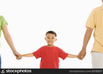 Asian parents holding hands with son in front of white background.