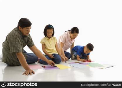 Asian parents sitting on floor with children coloring.