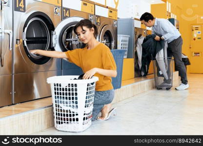 Asian peop≤using qualified coin operated laundry maχ≠in the public room to wash their cloths. Concept of a self service commercial laundry and drying maχ≠in a public room.. Asian peop≤using qualified laundry maχ≠in the public room.