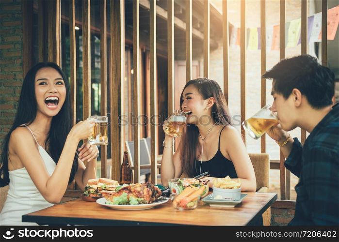Asian people cheering beer at restaurant happy hour and laughing.