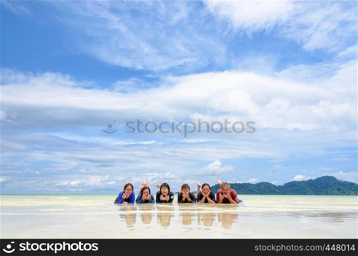 Asian people group adult and teens are family, Happy life enjoy by lying together on the beach on blue sky background, vacation in summer holiday at Ko Lipe and Ra Wi island, Tarutao, Thailand. Happy family lying together on the beach, Thailand