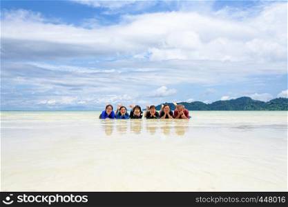 Asian people group adult and teens are family, Happy life enjoy by lying together on the beach of Ra Wi island during the sea travel vacation in summer holiday at Ko Lipe, Tarutao, Satun, Thailand. Happy family lying together on the beach, Thailand