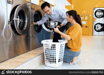 Asian people using qualified coin operated laundry machine in the public room to wash their cloths. Concept of a self service commercial laundry and drying machine in a public room.. Asian people using qualified laundry machine in the public room.