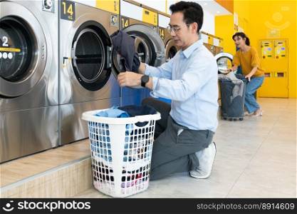 Asian people using qualified coin operated laundry machine in the public room to wash their cloths. Concept of a self service commercial laundry and drying machine in a public room.. Asian people using qualified laundry machine in the public room.
