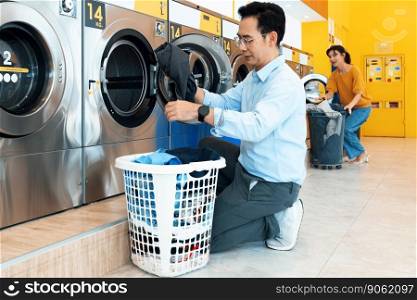 Asian people using qualified coin operated laundry machine in the public room to wash their cloths. Concept of a self service commercial laundry and drying machine in a public room.. Asian people using qualified laundry machine in the public room.