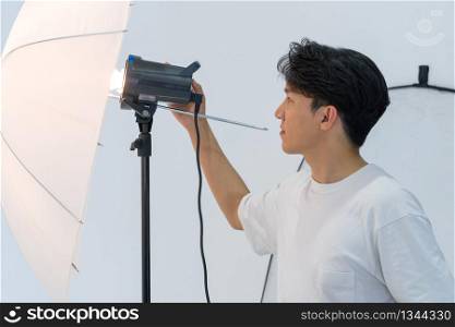 Asian photographers are adjusting the brightness of lights for shooting fashion models in the studio.