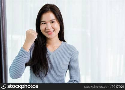 Asian portrait happy beautiful woman healthy smiling face long hair raise hand make success or winning yes gesture, studio shot looking to camera at home and have a copy space for your text