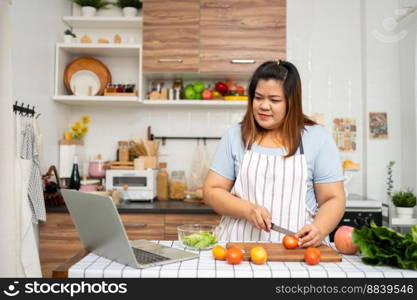 Asian Pregnant learn how to cook healthy meals from the Internet in kitchen, Fat women prepare a vegetable salad for diet food and lose weight. Concept of healthy eating