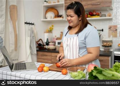 Asian Pregnant learn how to cook healthy meals from the Internet in kitchen, Fat women prepare a vegetable salad for diet food and lose weight. Concept of healthy eating
