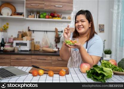 Asian Pregnant learn how to cook healthy meals from the Internet in kitchen, Fat women prepare a vegetable salad for diet food and lose weight. Concept of healthy eating