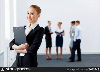 Asian pretty business woman with folder. Asian young business woman holding folder with colleagues at background