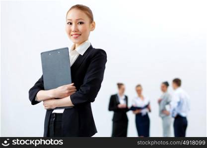 Asian pretty business woman with folder. Asian young business woman holding folder with colleagues at background