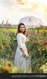 Asian pretty woman with white umbrella in tomatoes garden. woman with white umbrella