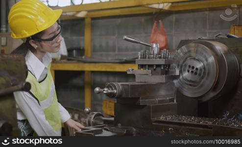 Asian professional mechanical engineer or operation woman wearing uniform goggles safety working on workshop metal lathe industrial manufacturing factory, Heavy industry lathe worker woman