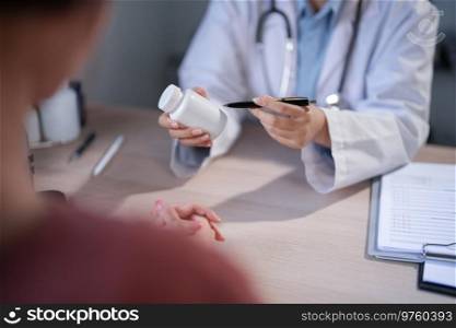 Asian psychologist women pointing on pills bottle to explaining medicine and prescription to female patient while giving counseling about medical and mental health therapy to female patient in clinic.