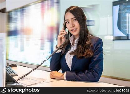 Asian reception recieving the call at the showroom counter for service the customer via telephone,