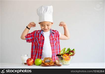 Asian red shirt little boy show action of feel stronger with various types of vegetable and fruits with healthy food concept for children.