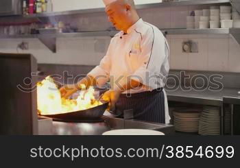 Asian restaurant, chinese chef cooking food, man as professional cook working, stir frying, preparing sauteed vegetables in pot on flame, fire, stove. Portrait, looking and smiling at camera. 24of27