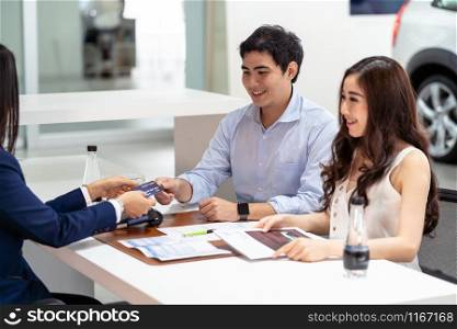 Asian Saleswoman recieving the credit card from couple customer when decision buy the new car after sign buy contract in showroom, credit card mockup
