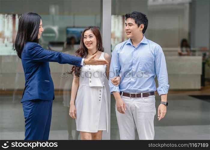 Asian Saleswoman welcoming the couple customer to checking the car infront of showroom,
