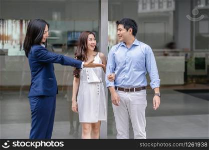 Asian Saleswoman welcoming the couple customer to checking the car infront of showroom,