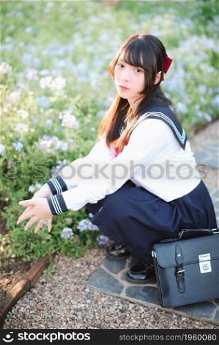 Asian school girl sitting with flower garden background