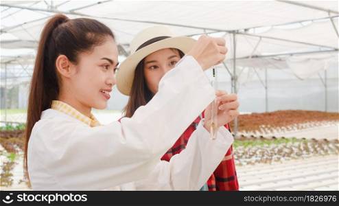 Asian scientist woman check chemical inspection soil PH tester in organic farm and show result to the owner in greenhouse, Woman farmer in a garden, Concept for new technology in the cultivation.