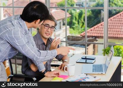 Asian senior and young business man working online on a modern laptop computer he looking the screen meeting online. Old and junior businessman using video call conference on desk table at office