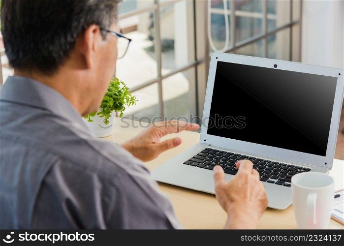 Asian senior business man working online on a modern laptop computer he looking at the screen for remote online studying. Old businessman people using the laptop to video call conference on desk table