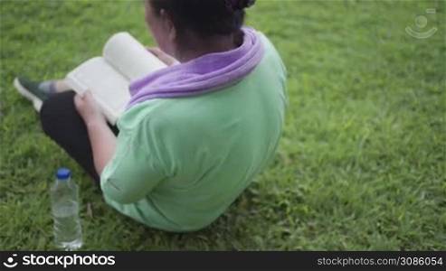 Asian senior female reading book sit down on grass field after exercise at the outdoor park, old age Leisure activity on free time, life motivation after retirement, Human wellness vitality