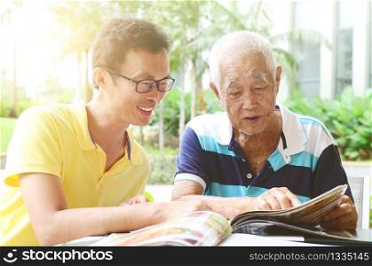 Asian senior man and son in the restaurant,ordering food by looking at the menu.