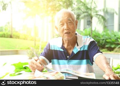Asian senior man in the restaurant,ordering food by looking at the menu.