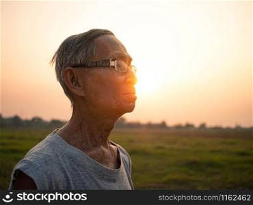 Asian senior man jogging in the park on sunset background. Healthcare concept.