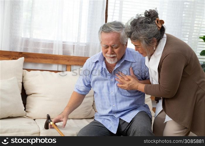Asian senior man with pain on heart on sofa in living room and take care by his wife, Health problem and feeling sick concept